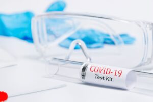 Close-up of a COVID-19 test kit with safety glasses and gloves, emphasizing safety in medical testing.