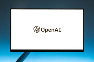 Minimalistic display of OpenAI logo on a monitor with a gradient blue background, representing modern technology.