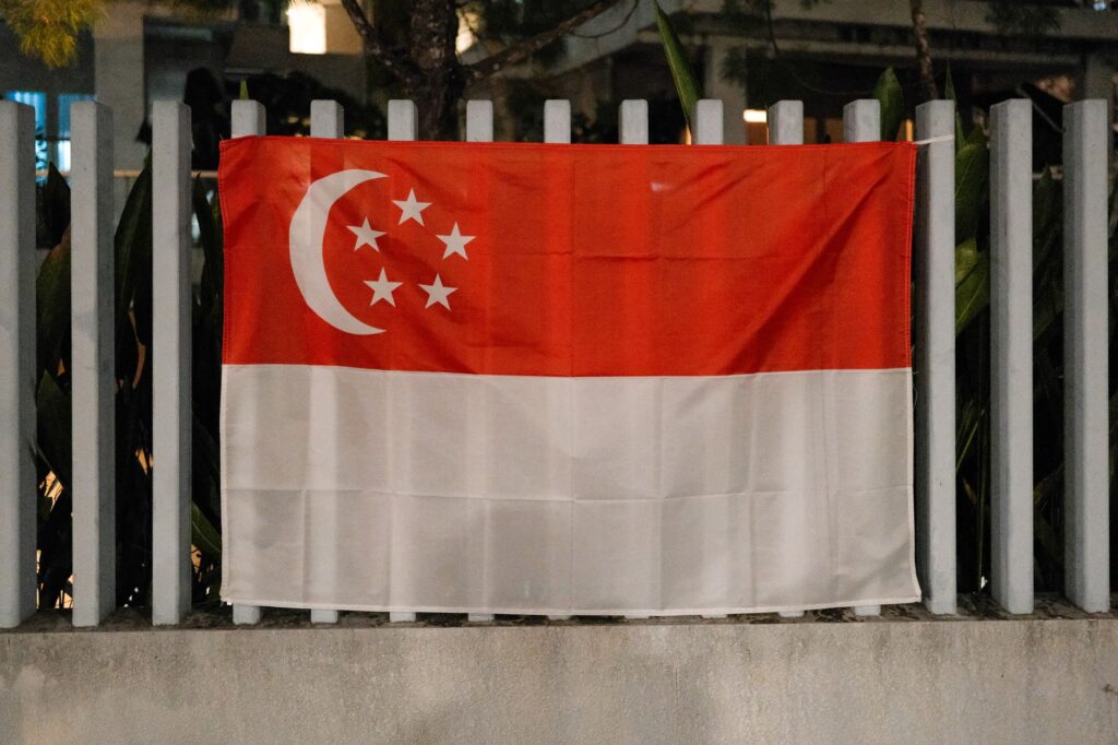 The Singapore flag displayed outdoors on a metal fence during the night.