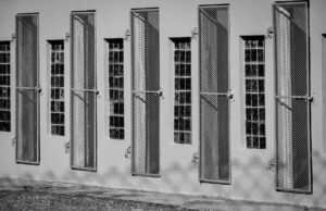 Monochrome image of barred windows on a building, depicting confinement and security.