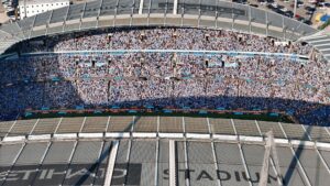 Aerial shot of Etihad Stadium filled with soccer fans in Manchester, UK.
